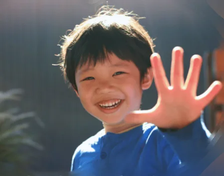 Un garçon souriant fait coucou de la main