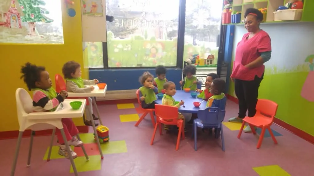 Des tout-petits prennent leur repas à la garderie avec leur éducatrice